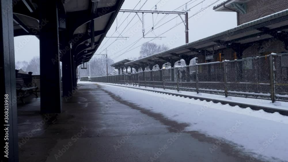 Long static shot of snow falling at a vacant train station in New Jersey