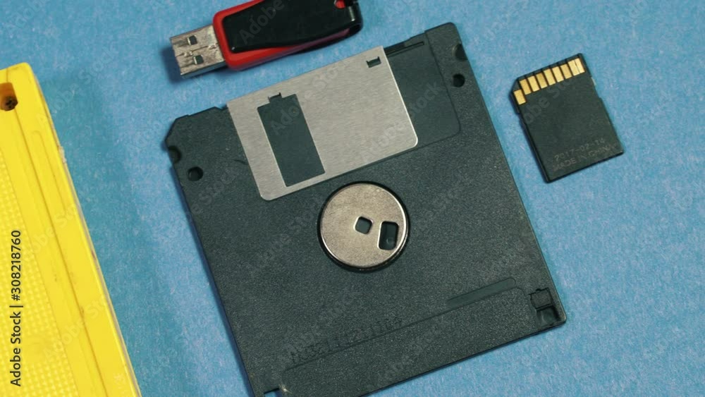 Evolution of memory storage devices, from VHS Tape and Audio Cassette, Film, Floppy disk to USB flash stick and SD memory card. blue retro background 