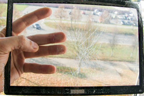 Looking through the broken touch screen damaged tablet computer. Service engineer holds a screen removed for replacement in his hand