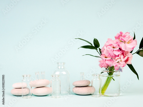 pink flowers in a vase, next to the Zen stones, tubes of oils, the theme of Spa and relaxation