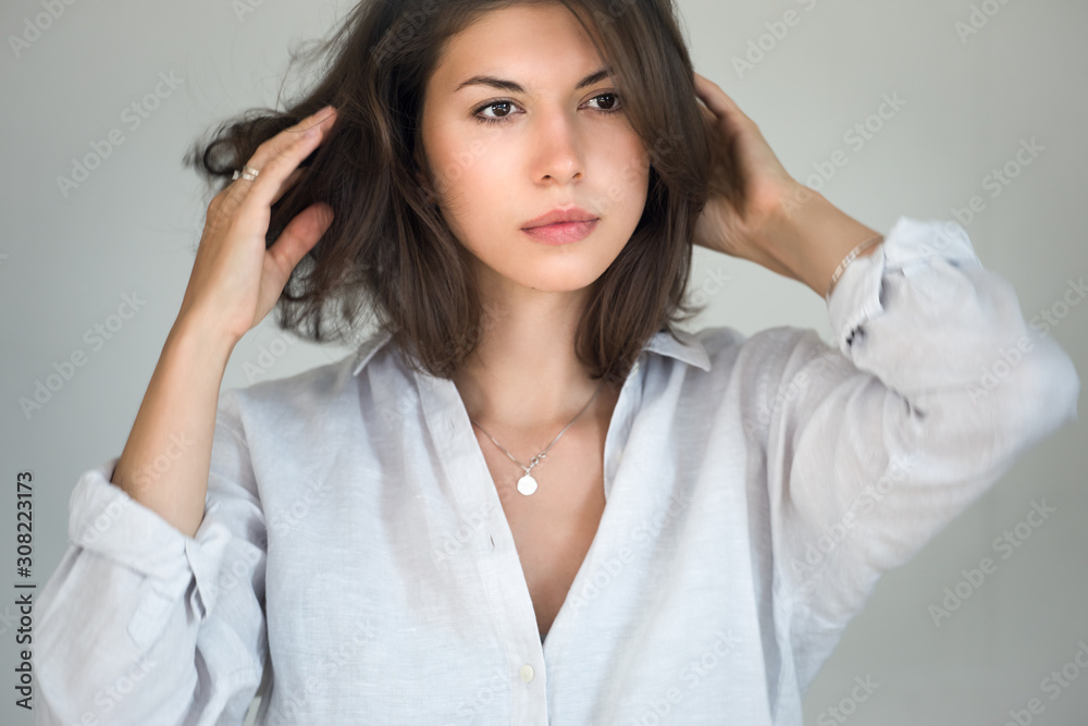 Portrait of a young successful woman with dark hair. The woman straightens her hair with her hands. Portrait of a young successful woman with dark hair. The woman straightens her hair with her hands.