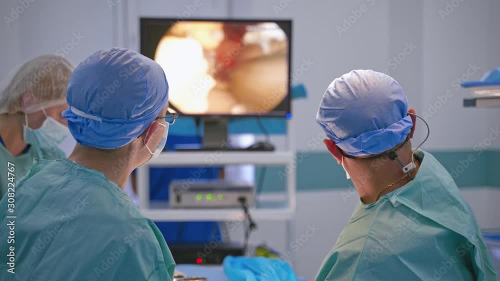 Surgery on the screen of a monitor. Professional surgeons perform an operation and looking on the screen of a modern device. New medical technologies.