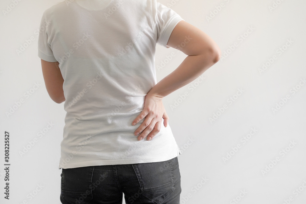 Close-up view of caucasian woman with pain in kidneys isolated on a white background. Girl with backache clasping her hand to her lower back. Woman suffering from ribbing pain. Close-up view of caucasian woman with pain in kidneys isolated on a white background. Girl with backache clasping her hand to her lower back. Woman suffering from ribbing pain.