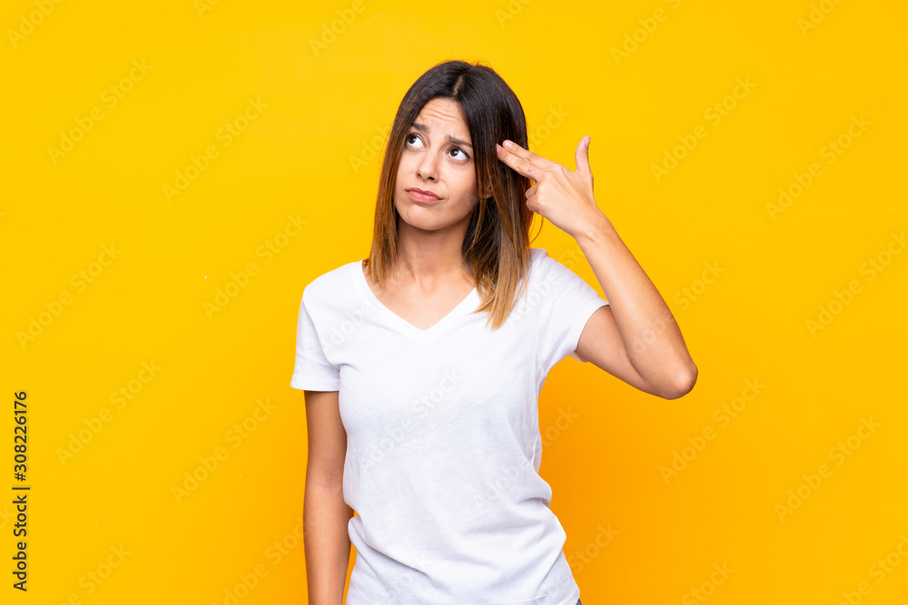 Young woman over isolated yellow background with problems making suicide gesture Young woman over isolated yellow background with problems making suicide gesture