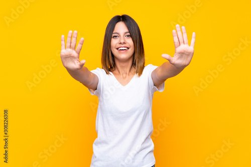 Young woman over isolated yellow background counting ten with fingers