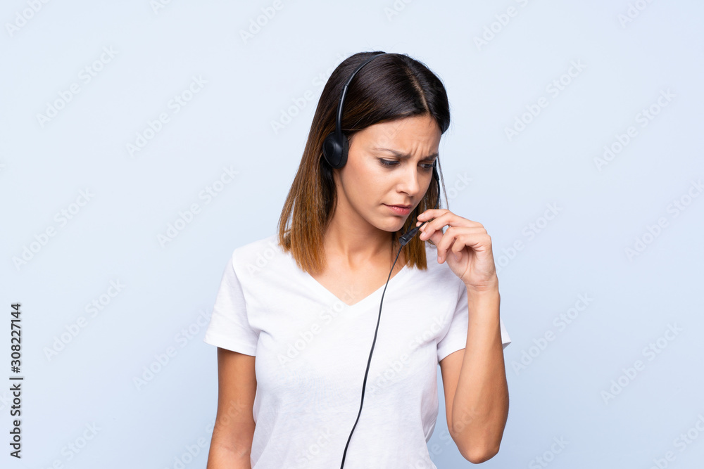Young woman over isolated blue background working with headset Young woman over isolated blue background working with headset