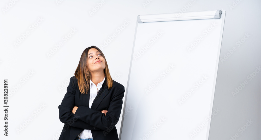Young woman giving a presentation on white board making doubts gesture while lifting the shoulders Young woman giving a presentation on white board making doubts gesture while lifting the shoulders