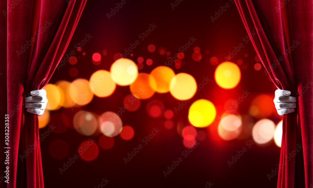 Bokeh lights behind drapery curtain and hand opening it