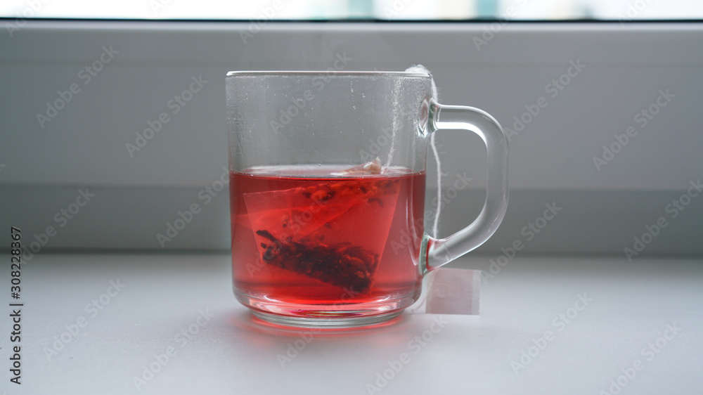 bag of fruit red tea is brewed in transparent glass cup bag of fruit red tea is brewed in transparent glass cup