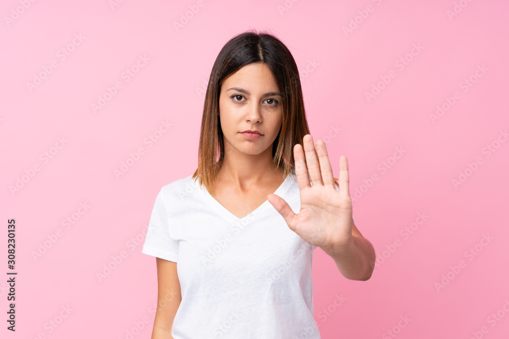 Young woman over isolated pink background making stop gesture Young woman over isolated pink background making stop gesture