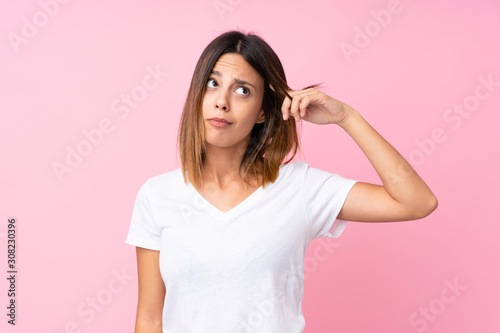 Young woman over isolated pink background making the gesture of madness putting finger on the head