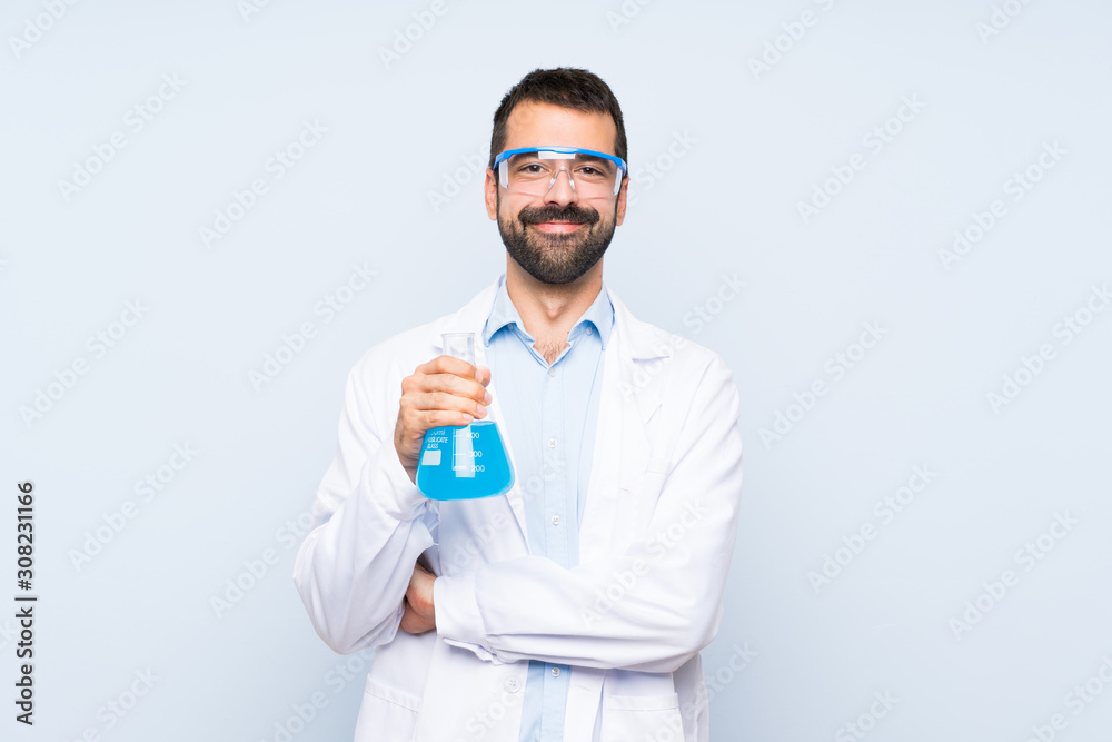 Young scientific holding laboratory flask over isolated background keeping the arms crossed in frontal position Young scientific holding laboratory flask over isolated background keeping the arms crossed in frontal position