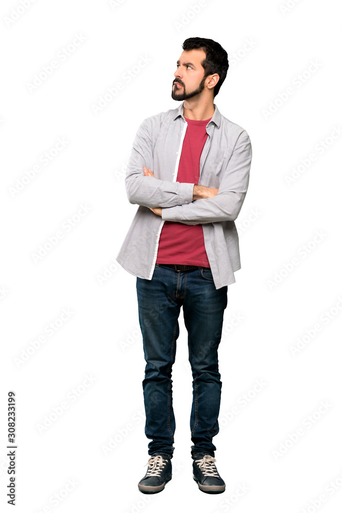 Full-length shot of Handsome man with beard with confuse face expression over isolated white background Full-length shot of Handsome man with beard with confuse face expression over isolated white background