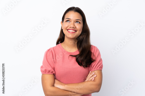 Young Colombian girl over isolated white background looking up while smiling