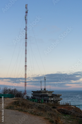 High tower. Telecommunications antenna on the high sea shore. Early autumn morning. Mainly cloudy.