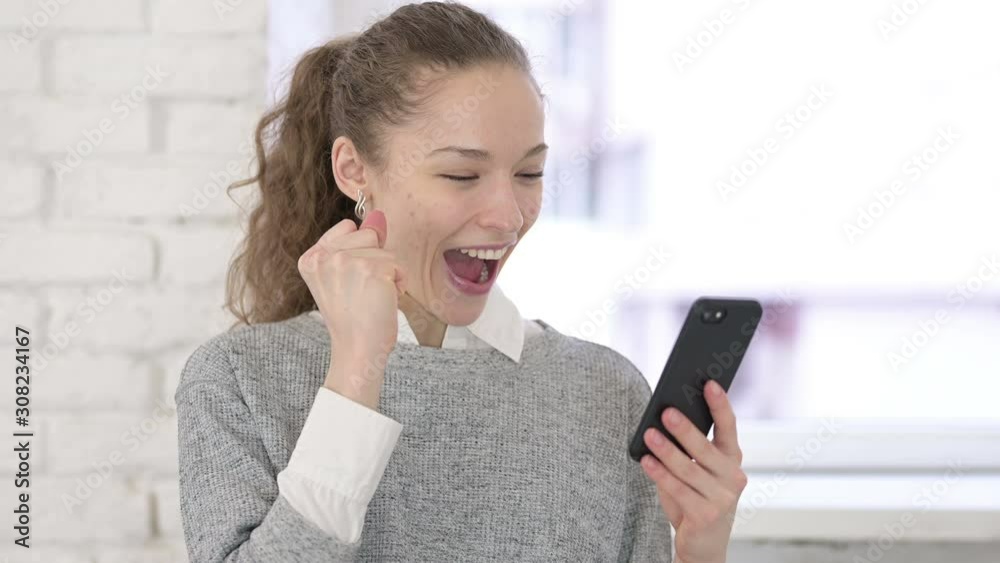 Portrait of Beautiful Young Latin Woman Celebrating Success on Smartphone Portrait of Beautiful Young Latin Woman Celebrating Success on Smartphone