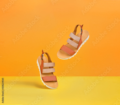 a pair of dancing yellow female leather sandals on a yellow-orange background for a banner with a copy space.