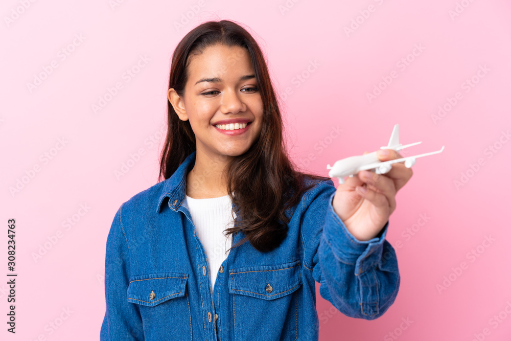 Young Colombian girl holding a toy airplane over isolated background Young Colombian girl holding a toy airplane over isolated background