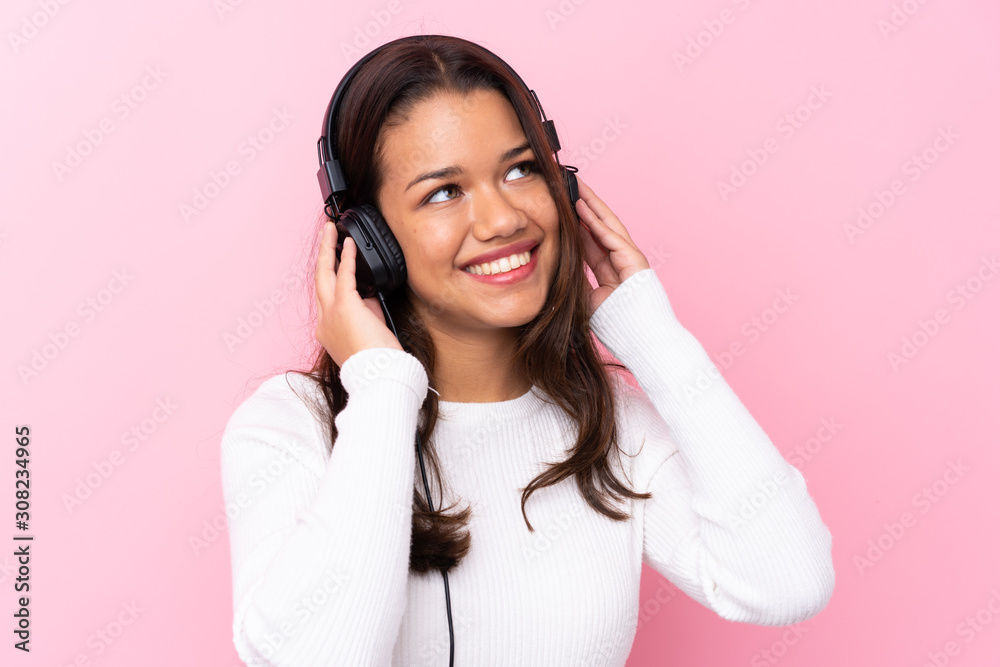 Young woman with earphones over isolated pink wall Young woman with earphones over isolated pink wall