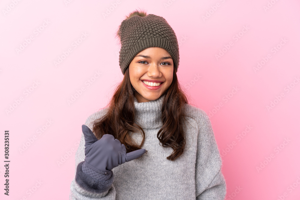 Young Colombian girl with winter hat over isolated pink wall making phone gesture Young Colombian girl with winter hat over isolated pink wall making phone gesture