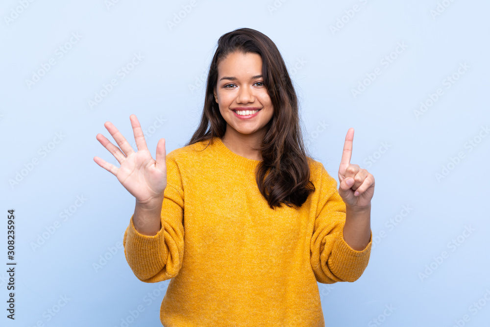 Young Colombian girl with sweater over isolated blue background counting six with fingers Young Colombian girl with sweater over isolated blue background counting six with fingers