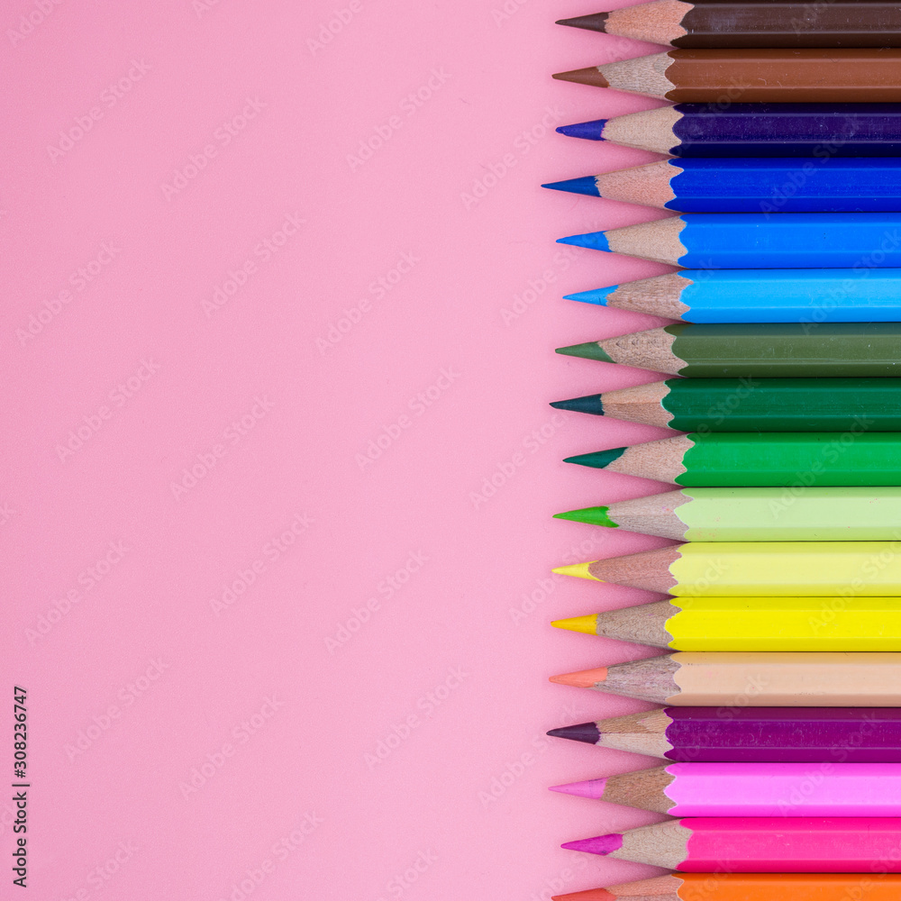 top view of colored crayons and letters spread on pink background conceptual photo top view of colored crayons and letters spread on pink background conceptual photo