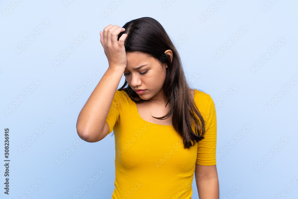 Young Colombian girl over isolated blue background having doubts with confuse face expression Young Colombian girl over isolated blue background having doubts with confuse face expression