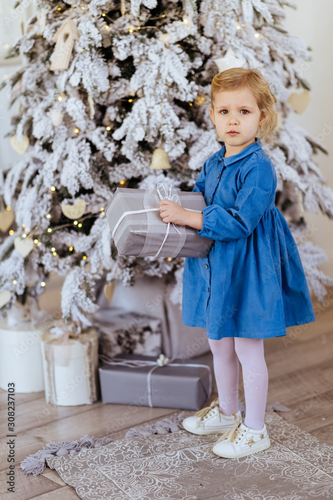 Little girl with Christmas gifts near a Christmas tree at home Little girl with Christmas gifts near a Christmas tree at home