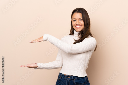 Young Colombian girl over isolated background holding copyspace to insert an ad