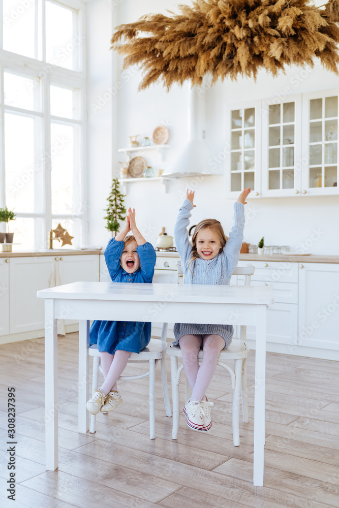 two children sitting on the kitchen table and eating candies. Mother with daughter and toddler son having breakfast at home. Happy lifestyle family moments. two children sitting on the kitchen table and eating candies. Mother with daughter and toddler son having breakfast at home. Happy lifestyle family moments.
