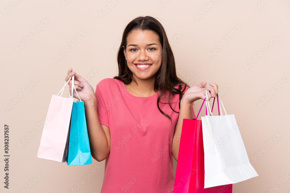 Young Colombian girl with shopping bag over isolated background holding shopping bags and smiling Young Colombian girl with shopping bag over isolated background holding shopping bags and smiling