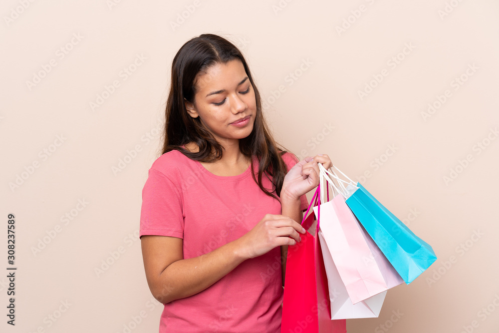 Young Colombian girl with shopping bag over isolated background holding shopping bags