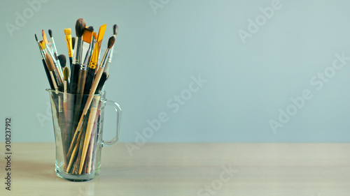 Paint brushes are in a glass jug on the table. Desktop wallpaper