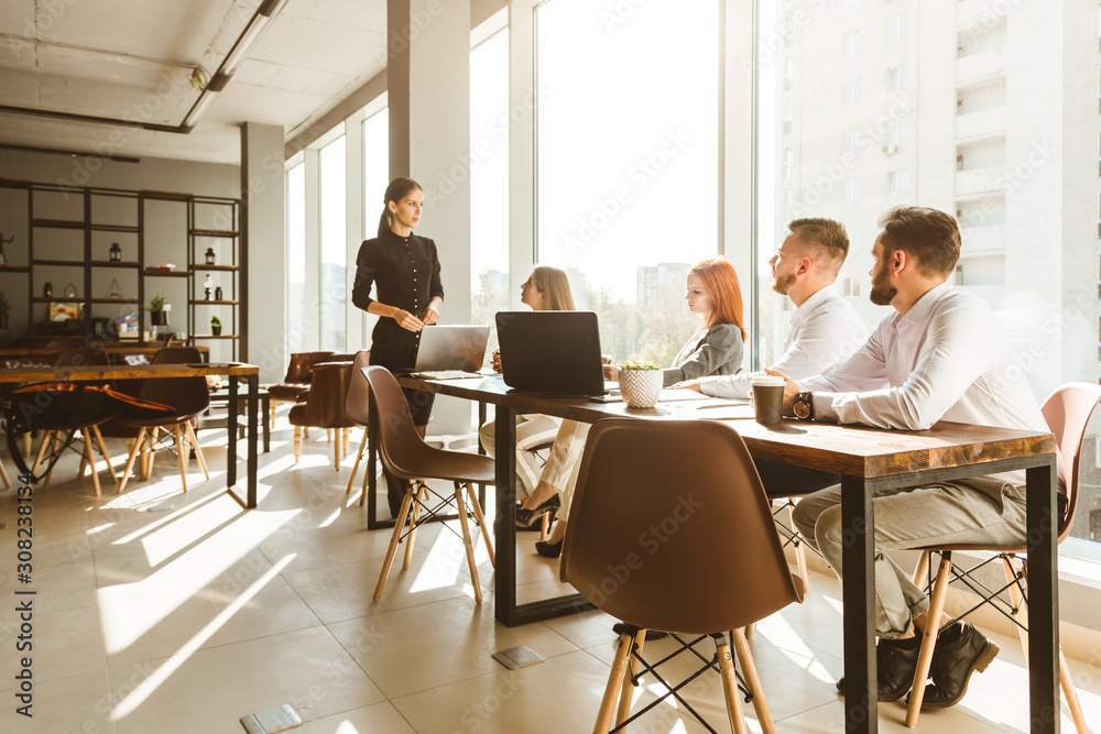 A team of young businessmen working and communicating together in an office. Corporate businessteam and manager in a meeting. desktop against the background of the pan window, free space for text