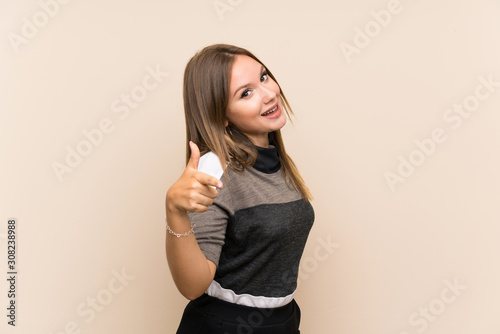 Teenager girl over isolated background with thumbs up because something good has happened