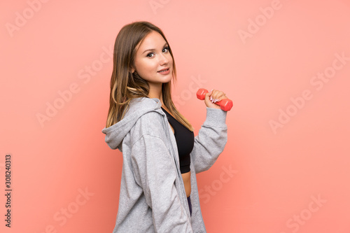 Fototapeta Naklejka Na Ścianę i Meble -  Teenager sport girl making weightlifting over isolated pink background smiling a lot