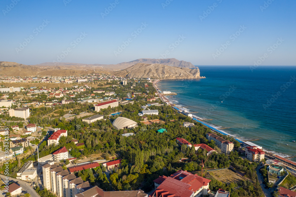 The resort town of Sudak in Crimea from a height view of the coastline with beaches and mountains in the distance