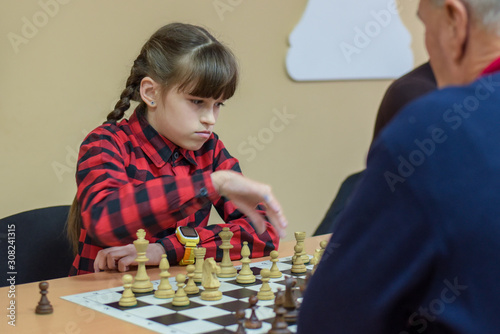 The girl plays chess. Figures on a chessboard. Game of chess.