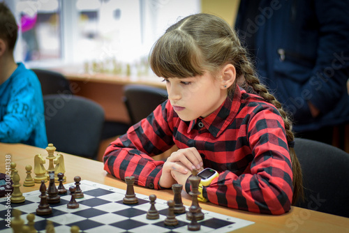 The girl plays chess. Figures on a chessboard. Game of chess.
