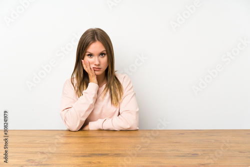 Teenager girl in a table unhappy and frustrated