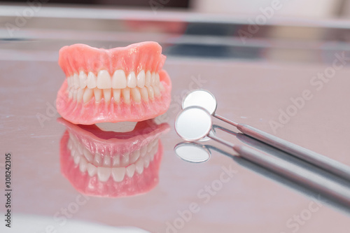 Two dentures. Instruments and dental hygienist checkup concept with teeth model dentures and mouth mirror. Regular dentist checkups