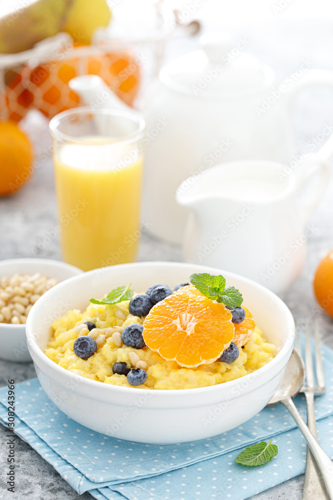Corn porridge with fresh blueberry, orange and pine nuts in bowl served for breakfast Corn porridge with fresh blueberry, orange and pine nuts in bowl served for breakfast