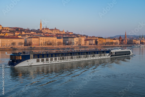 A large tourist ship floats along the Danube River in the center of Budapest, Hungary. Budapest at sunrise.