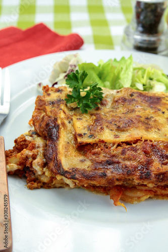 lasagna with bolognese and green salad on a plate