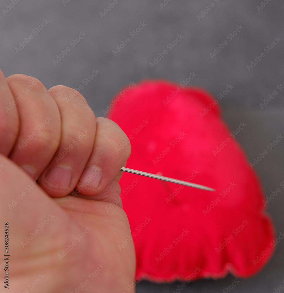 red pincushion and a large sewing needle, needle spell, red pincushion and a large sewing needle, needle spell,