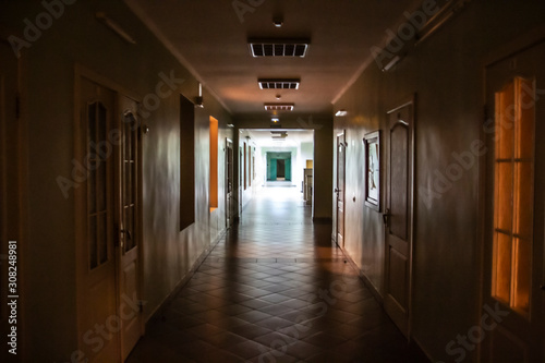 Dark corridor in the hospital. A long terrible corridor with light from the windows. Scary way.