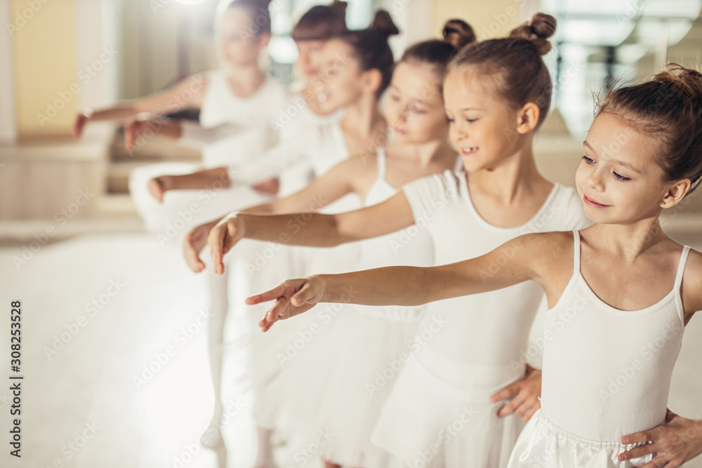 little kids ballerinas in studio, wearing white tutu skirts, stand in pose, performing classic ballet dance, smooth movements - obrazy, fototapety, plakaty 