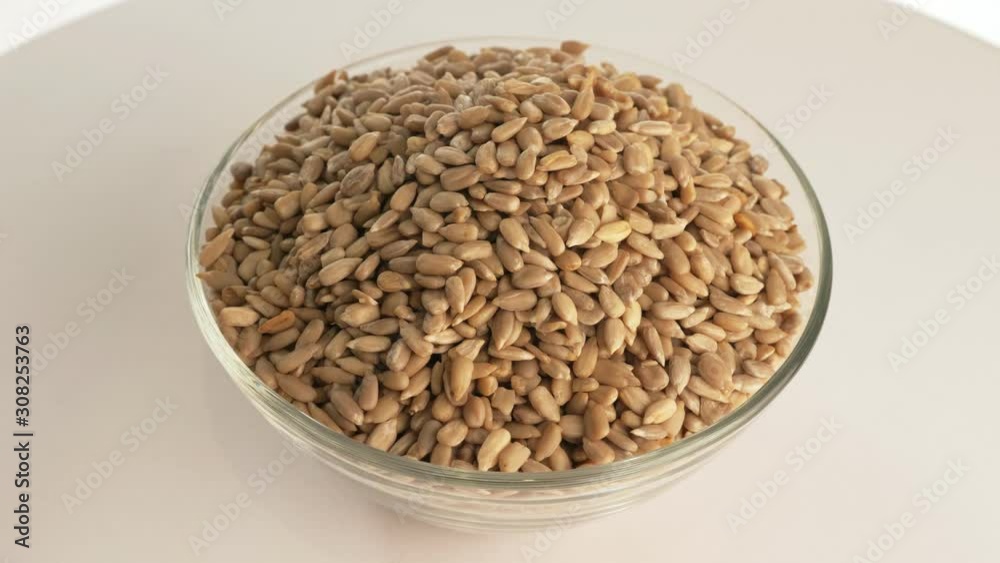 Nuts sunflower rotate are on a table in a plate. Snack in transparent dish on an isolated white background are spinning moving. Delicious and healthy protein-rich diet food. Nuts sunflower rotate are on a table in a plate. Snack in transparent dish on an isolated white background are spinning moving. Delicious and healthy protein-rich diet food.