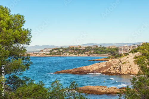 Seascape  blue sea with rocky shores and green trees. Spain  Costa Dorada  Salou