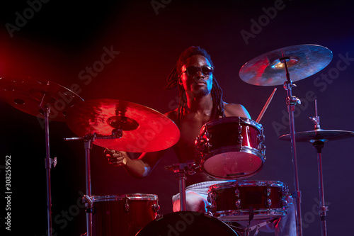 portrait of professional drummer man vigorous and expressive  emotional playing on drum set isolated in studio